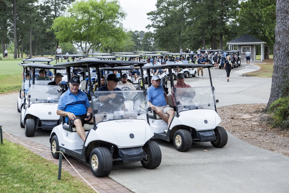 People driving golf cart during a golf tournament for nonprofits.