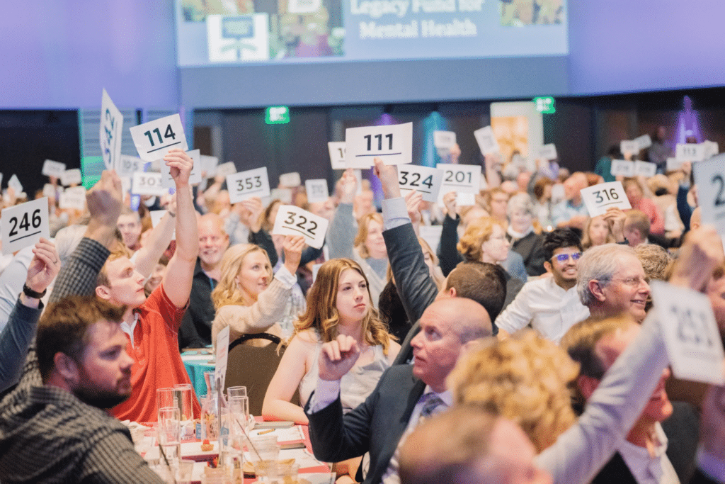 Many donors raising their paddles in a nonprofit auction.