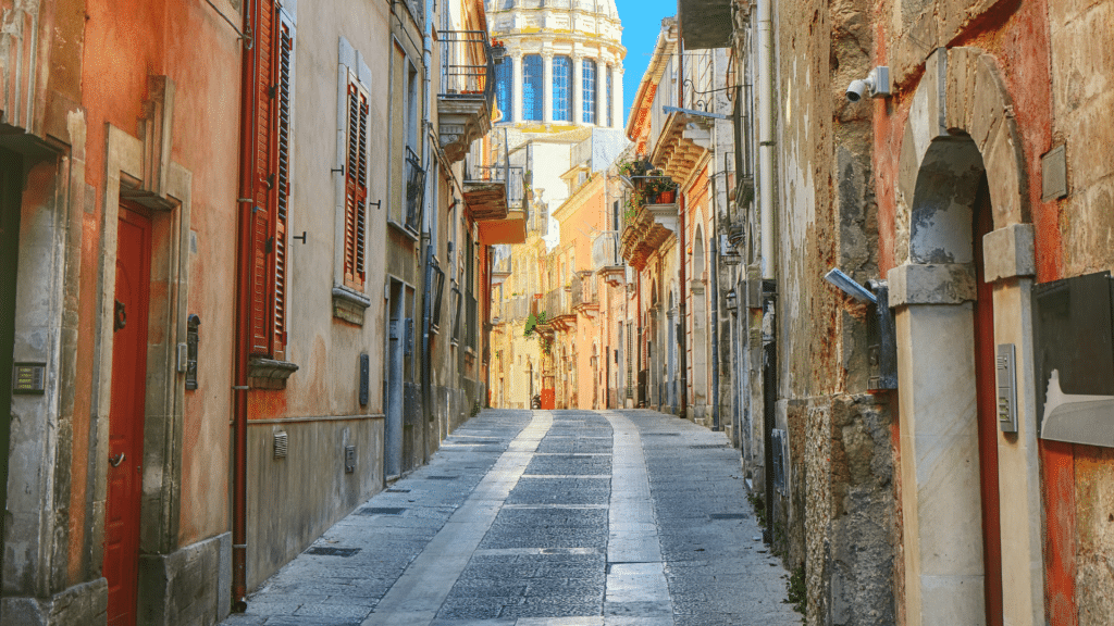 Charming cobblestone street lined with historic buildings in Ragusa, Sicily.