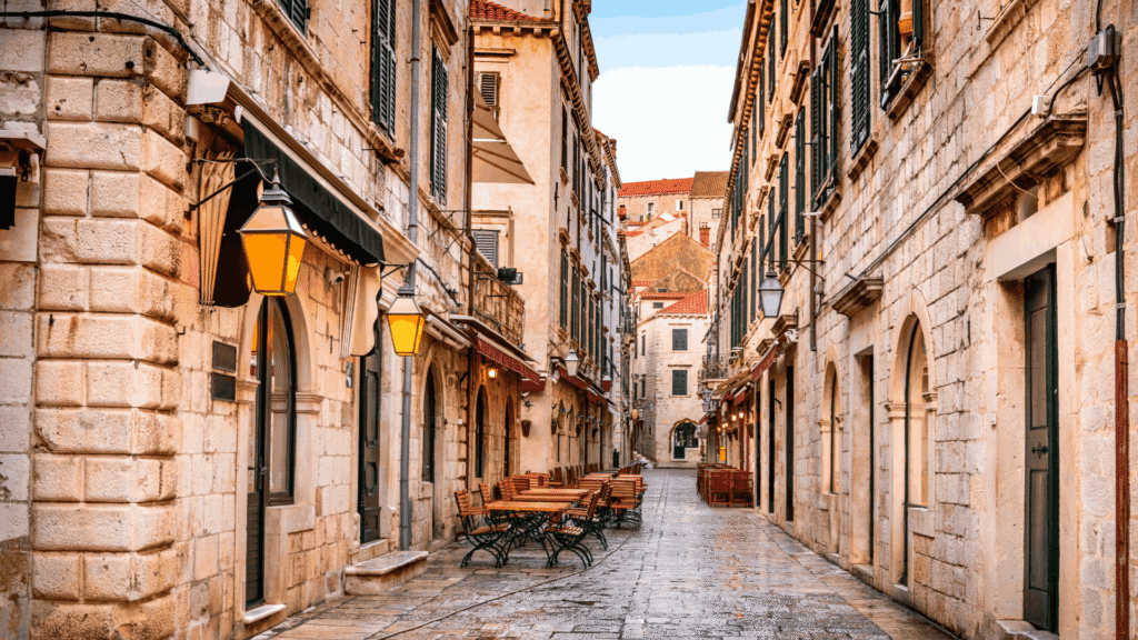 Stone-paved street lined with historic buildings and outdoor cafés in Dubrovnik Old Town, Croatia