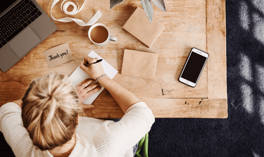Woman at desk writing post-event thank you notes to strengthen donor stewardship.